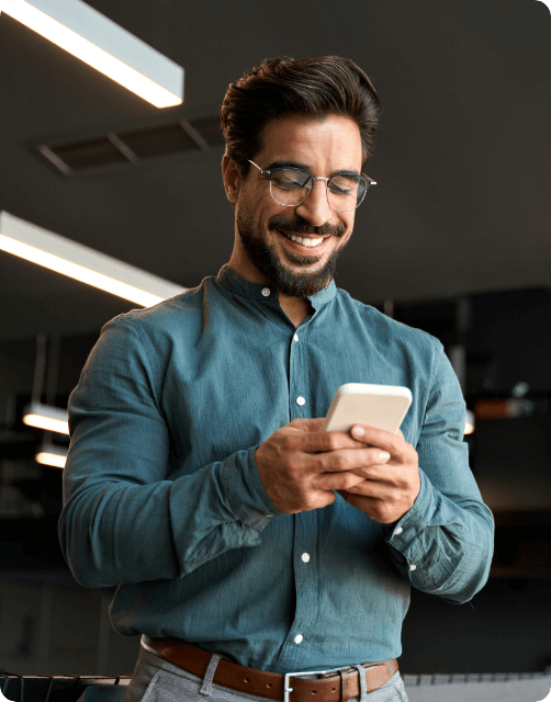 Smiling man using smartphone in modern office environment.